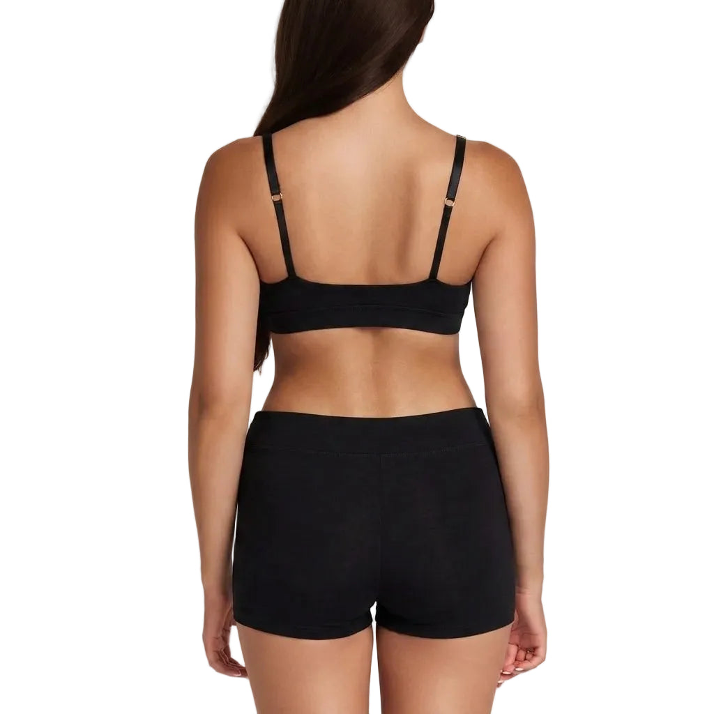 A woman shown from the back wearing a black sports bra and matching black shorts against a plain light background.