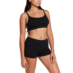 A woman modeling a black two-piece activewear set consisting of a scoop-neck sports bra and matching high-waisted shorts